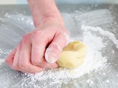 a person is kneading dough on top of a table with powdered sugar