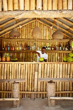 a man standing behind a bar filled with lots of fruit