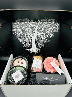 an open box with various items in it and a tree design on the back side