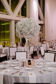 an elegant centerpiece with baby's breath flowers is displayed on a round table