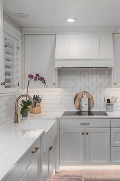 a kitchen with white cabinets and marble counter tops