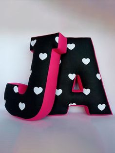 the letter j is decorated with white hearts and pink ribbon on black fabric, which matches the color of the letters