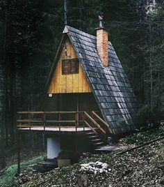 a small wooden cabin in the woods with stairs leading up to it's roof