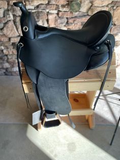 a black saddle sitting on top of a wooden table