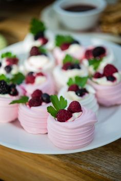 small desserts are arranged on a plate with berries and mint garnishes