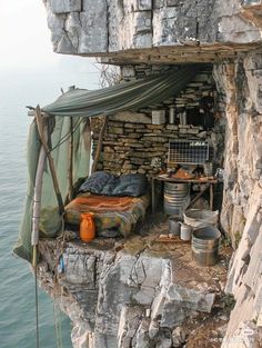 a bed sitting on top of a cliff next to the ocean under a tarp