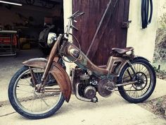 an old motorcycle parked in front of a garage