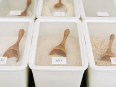 four bins with wooden spoons and rice in them