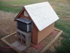 an air conditioner sitting in the middle of a yard next to a dog house