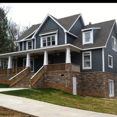 a gray house with white trim on the front porch and stairs leading up to it