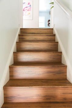 wooden stairs leading up to the first floor in a home with white walls and wood floors