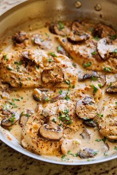 a pan filled with chicken and mushrooms covered in gravy on top of a table