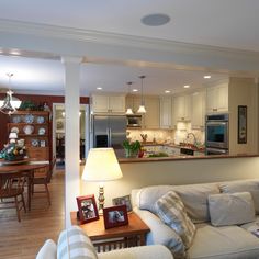 a living room filled with furniture next to a kitchen and dining room table in front of it