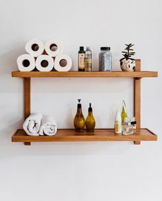 two wooden shelves filled with toilet paper and other bathroom items on top of each shelf