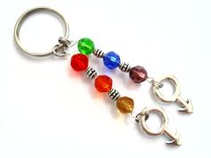 three different colored beads are attached to a metal keychain on a white surface