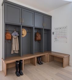 an entryway with several coats and boots on the bench in front of two wall - mounted lockers