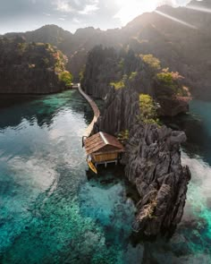 an aerial view of a dock in the middle of clear blue water with mountains in the background