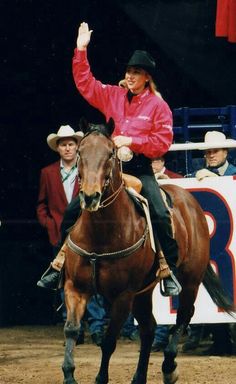 a man riding on the back of a brown horse in front of a group of people