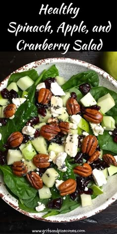 a bowl filled with spinach, apples and cranberry salad