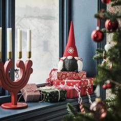 a window sill filled with presents next to a christmas tree and lit candles on top of it