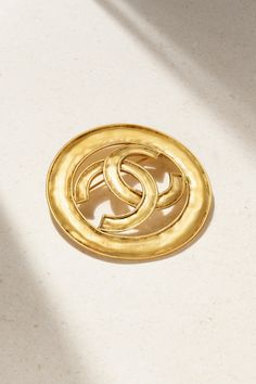 With over 40 years' experience in the vintage jewelry industry, Susan Caplan has a keen eye for sourcing and authenticating exquisite finds that you'll treasure for a lifetime. Marked and dated circa '94, this Chanel brooch is made from hammered gold-plated metal and detailed with the iconic 'CC' medallion. Pin yours to the lapel of your favorite blazer.  This Chanel item has been authenticated by Susan Caplan. Susan Caplan is not affiliated or endorsed by Chanel. Timeless Formal Jewelry With Gold-tone Logo Plaque, Luxury Round Brooches For Collectors, Gold-tone Logo Plaque Jewelry For Anniversary, Luxury Round Collectible Brooches, Gold Jewelry With Gold-tone Logo Plaque For Anniversary, Gold Jewelry With Logo For Anniversary, Timeless Jewelry Brooch As Gift, Designer Formal Brooch Jewelry, Timeless Jewelry Brooch For Gift