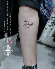 a person with a cross tattoo on their left leg and the word strength written in cursive font