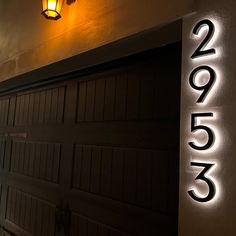 a black garage door with the number 2055 on it and a light hanging above