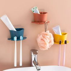 three toothbrushes are hanging on the wall next to a sink