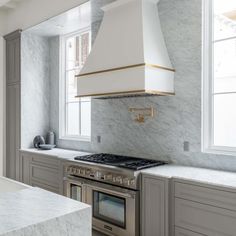 a kitchen with marble counter tops and stainless steel oven hoods, along with an island