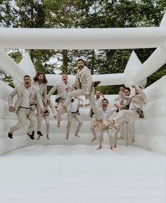 a group of men in suits jumping into the air on an inflatable structure