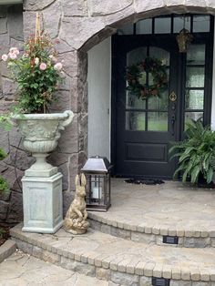 a rabbit statue sitting on the steps in front of a house with a black door