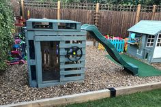 an outdoor play area with a slide and climbing frame in the back yard, next to a wooden fence