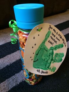 a jar filled with lots of candy next to a blue plastic cup on the floor