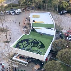 an aerial view of a starbucks building with green roofing and people walking around it