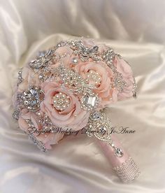 the bridal bouquet is adorned with swaro crystals and pink roses, as well as pearls