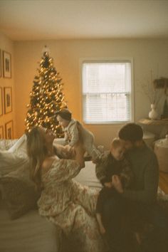 a family sitting on a couch in front of a christmas tree with the lights on