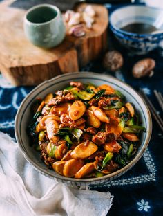 a bowl filled with pasta and vegetables on top of a blue cloth next to chopsticks