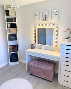 a white vanity with lights on it and a stool in front of the mirror that is lit up