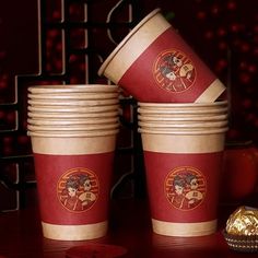 several cups with designs on them are stacked next to each other, and one has a gold foil wrapper