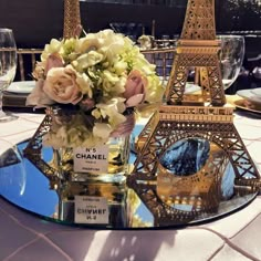 the table is set with flowers in front of the eiffel tower