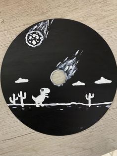 a black and white painting on a wooden surface with cactuses in the sky above it