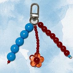 a red, orange and blue beaded keychain hanging from a metal hook