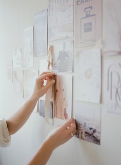 a woman placing pictures on the wall with her hands and holding them up to it