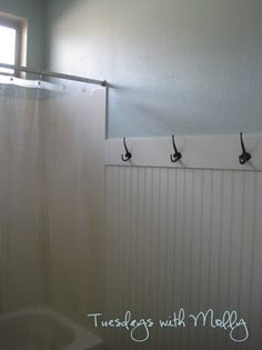 a bathroom with three hooks on the wall