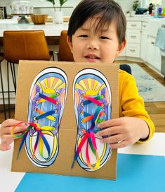 a young boy holding up an art piece