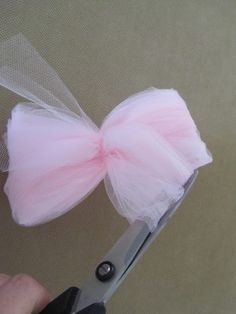 a person holding a pair of scissors with a pink bow on it