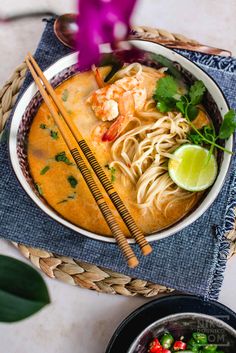 a bowl filled with noodles and shrimp next to chopsticks on top of a table