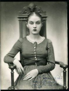 an old black and white photo of a woman sitting in a chair with her hands on her hips