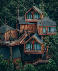 an aerial view of several wooden houses in the woods with trees surrounding them and stairs leading up to their upper floors