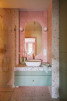 a bathroom with pink walls and marble counter top, mirror above the sink, and shower